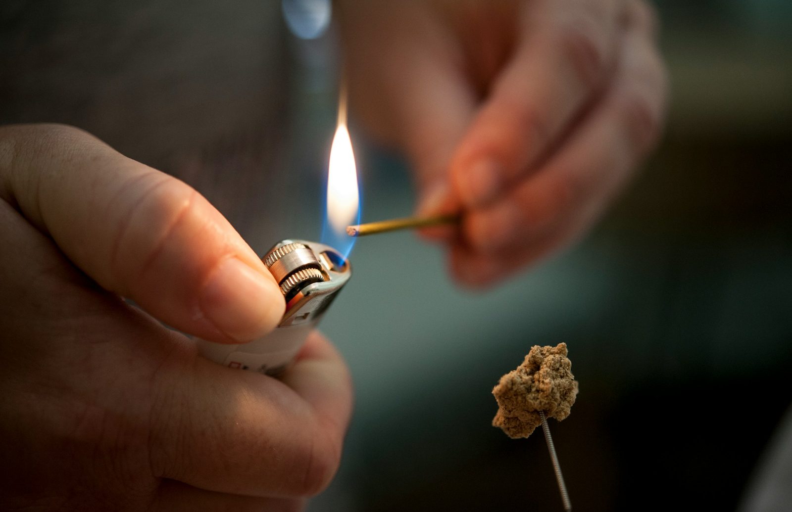 A practitioner lighting a small cone of moxa on the handle of an acupuncture needle